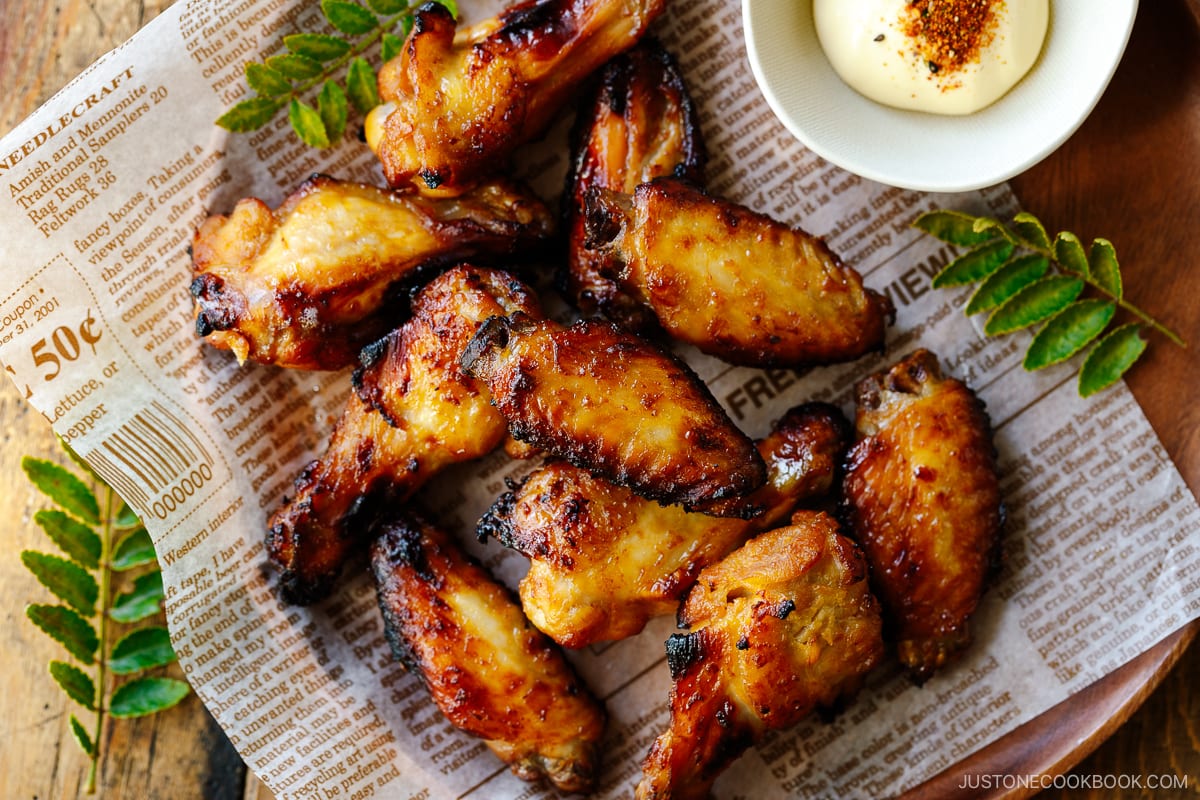 A round wooden plate containing Garlic Miso Chicken Wings.