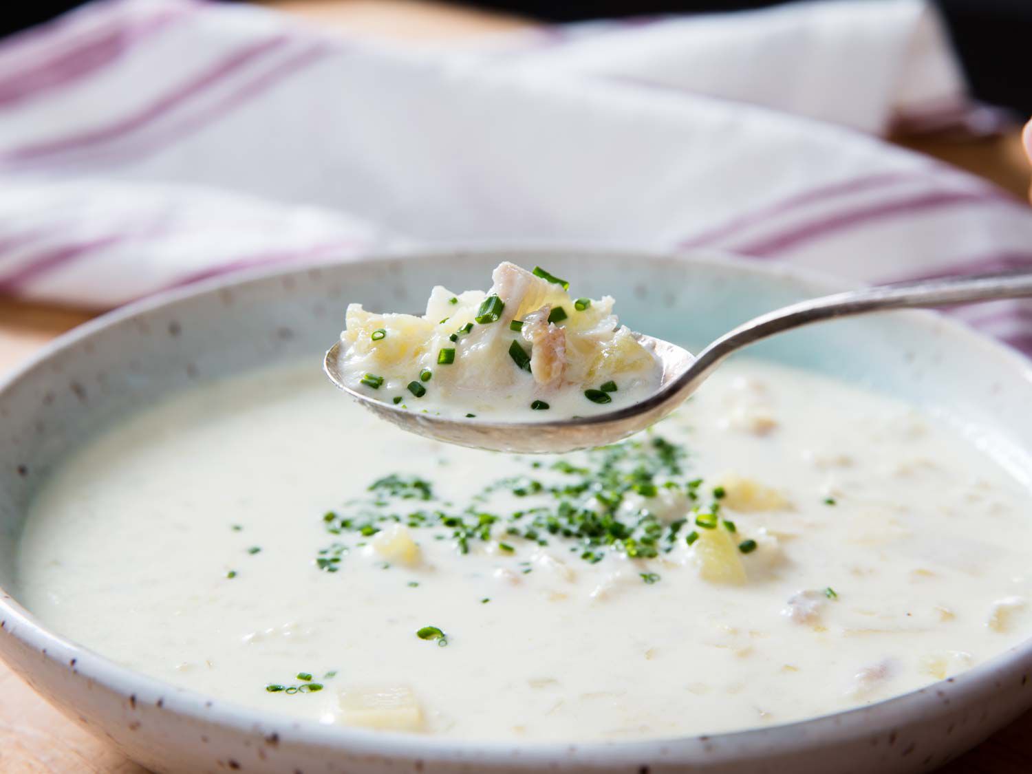 Cullen skink being lifted out of a bowl with a spoon.
