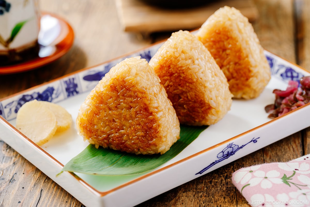 A rectangular plate containing three yaki onigiri (grilled rice balls).