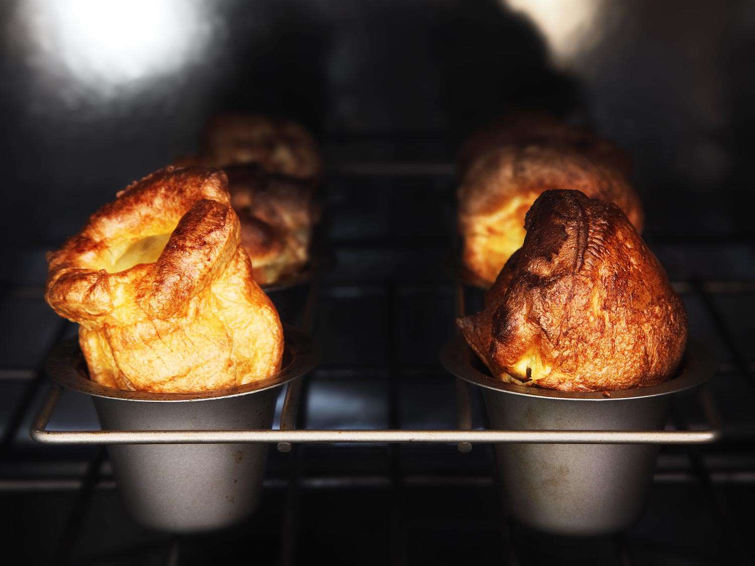 Two golden brown Yorkshire puddings side by side in oven