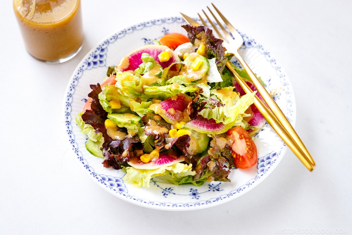 A plate of green salad along with a glass jar of homemade miso dressing.