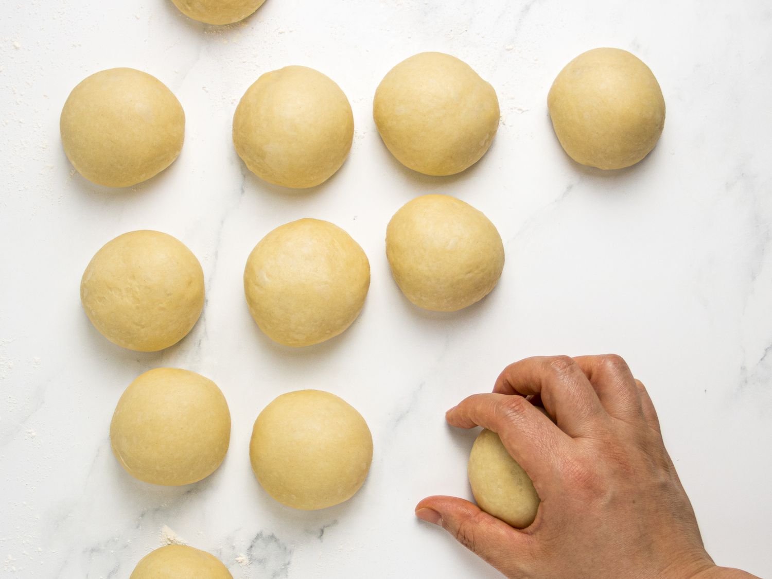 rolling dough into balls on a prepared surface 