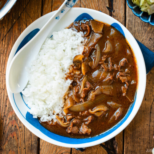 A round shallow bowl containing a bed of steamed rice and Hayashi Rice.