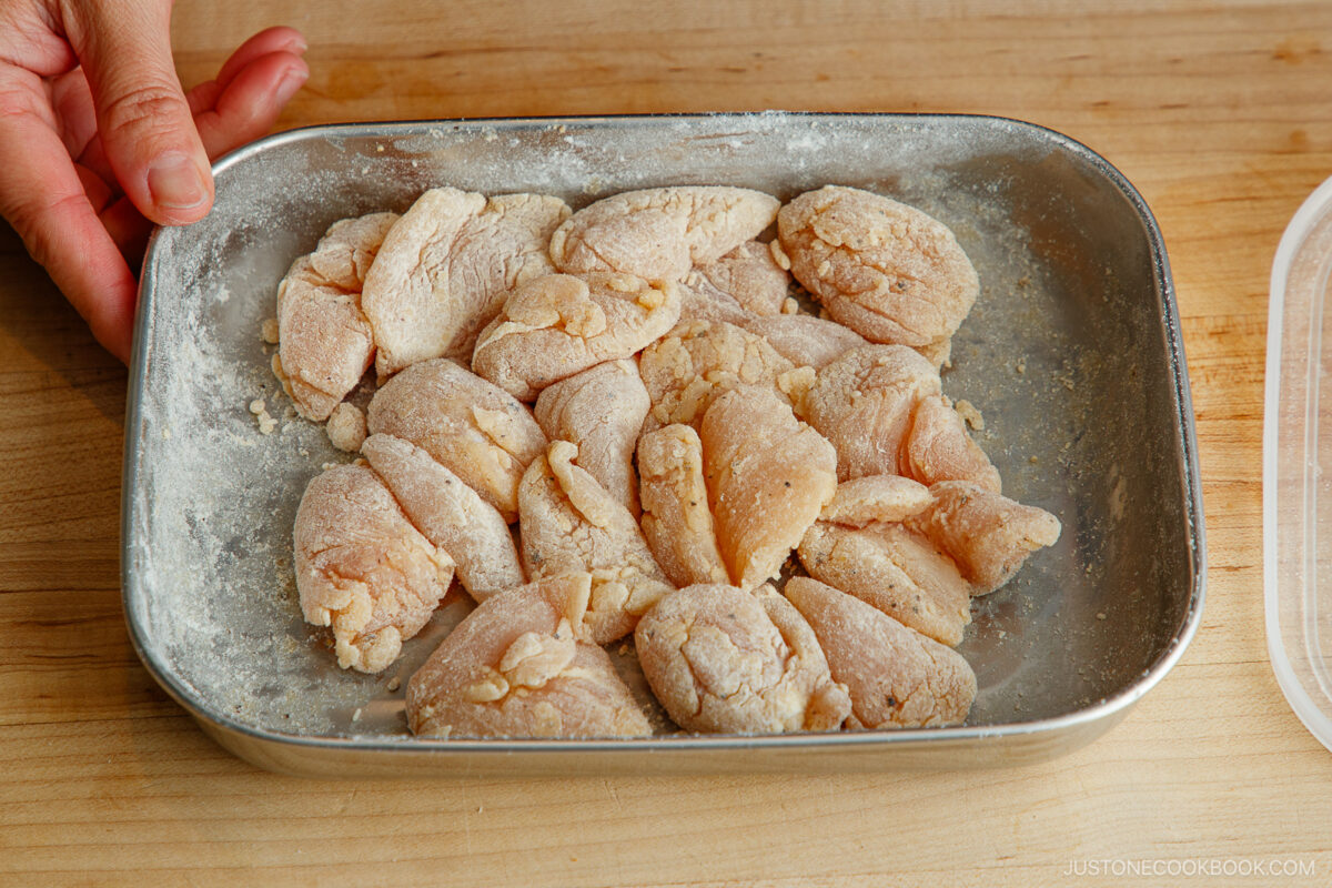 Coating the chicken with flour.