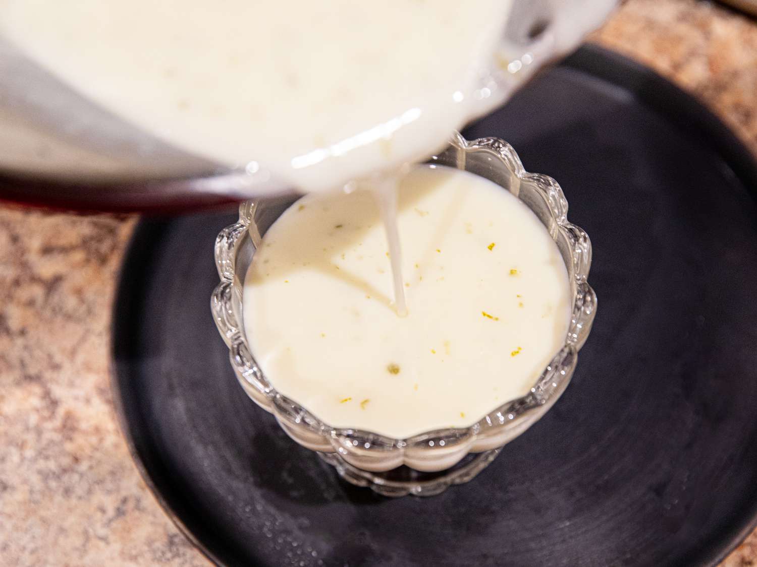 Pouring posset mixture into a cup. 