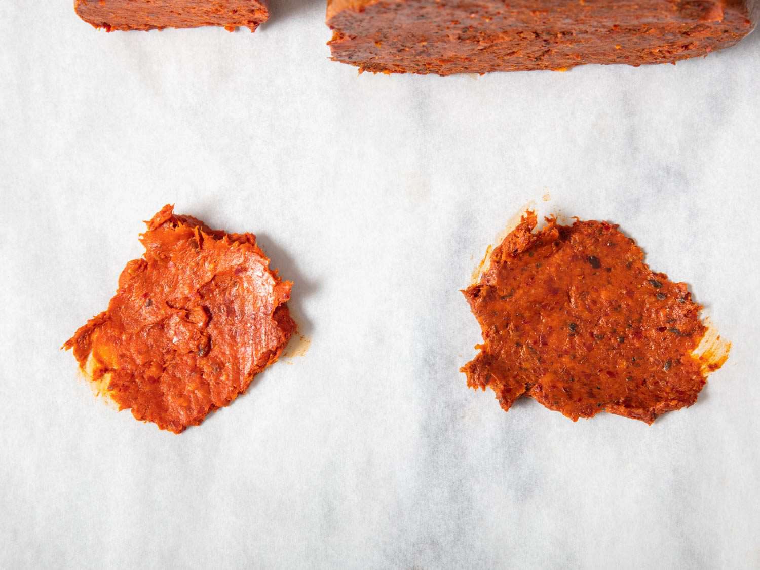 On the left, a smaller smear of 'nduja, aged for less time, remains a brighter red. The smear of orba 'nduja on the right ages longer, becoming a deeper red.