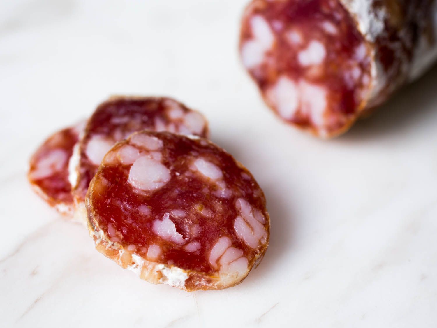 Close-up of sliced dry-cured salumi studded with fat