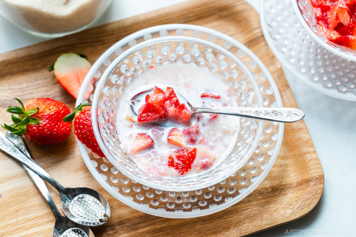 A glass bowl containing Japanese strawberry milk dessert with chunks of fresh strawberries.