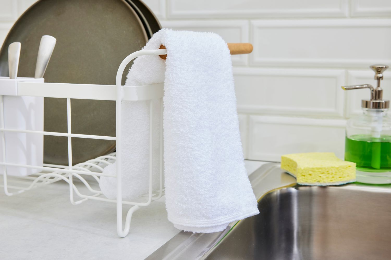 A white bar mop hanging off of the end of a dish rack.