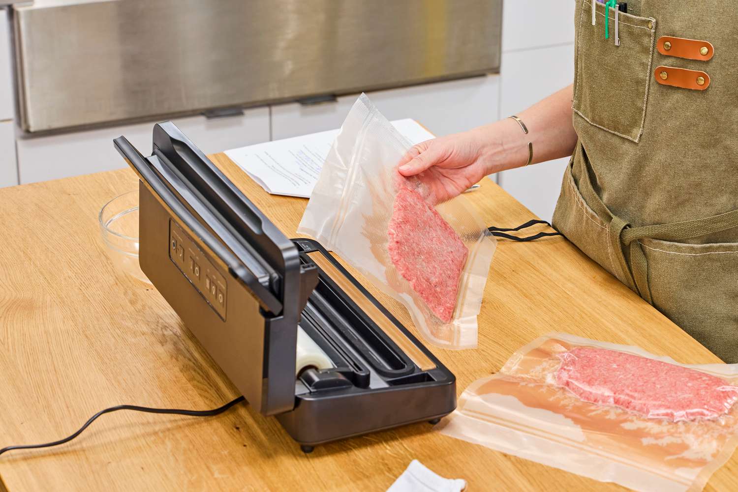 Two vacuum sealed bags of meat beside a vacuum sealer.