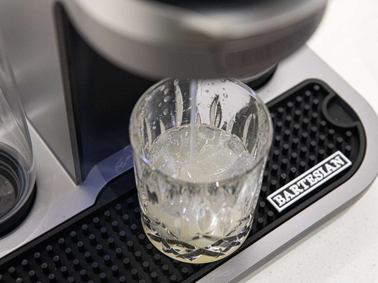 A closeup look at the Barestian making a cocktail and funneling it into a rock's glass