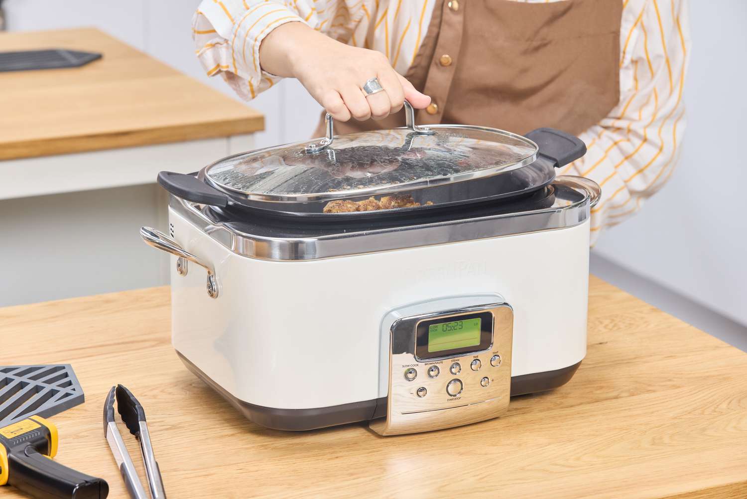 A person removes the lid of the GreenPan Elite 6-Quart Slow Cooker