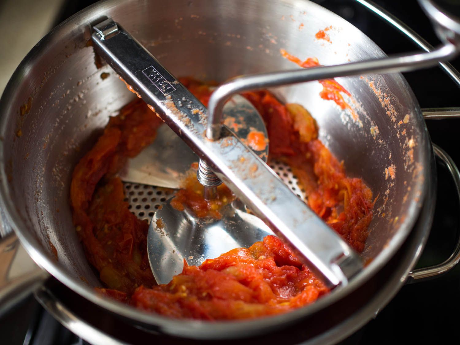 Fresh tomatoes going through a food mill to make passata.