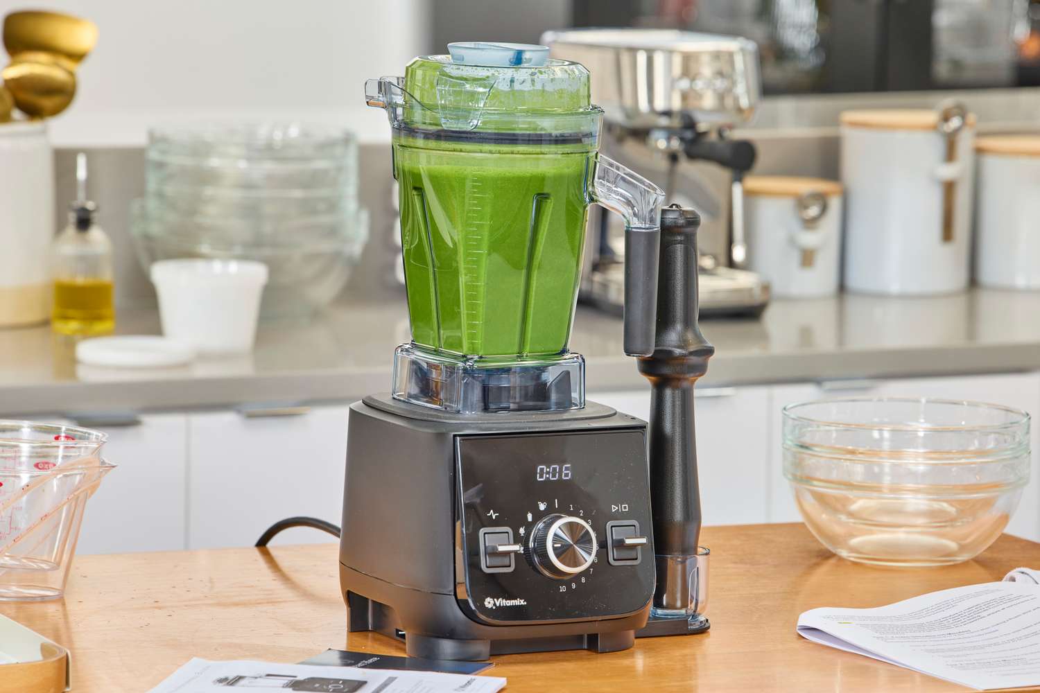 The Vitamix Ascent X2 containing green liquid on a wooden kitchen counter