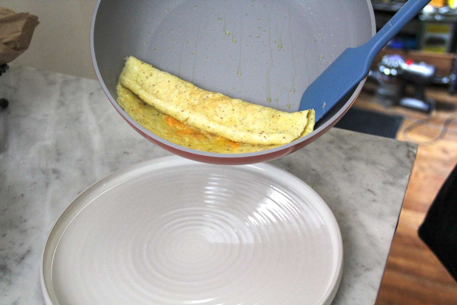 A spatula scooping food out of the Caraway Nonstick Ceramic Frying Pan onto a plate