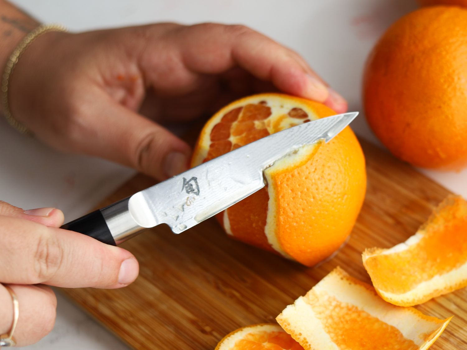 A person peeling an orange with the Shun paring knife.
