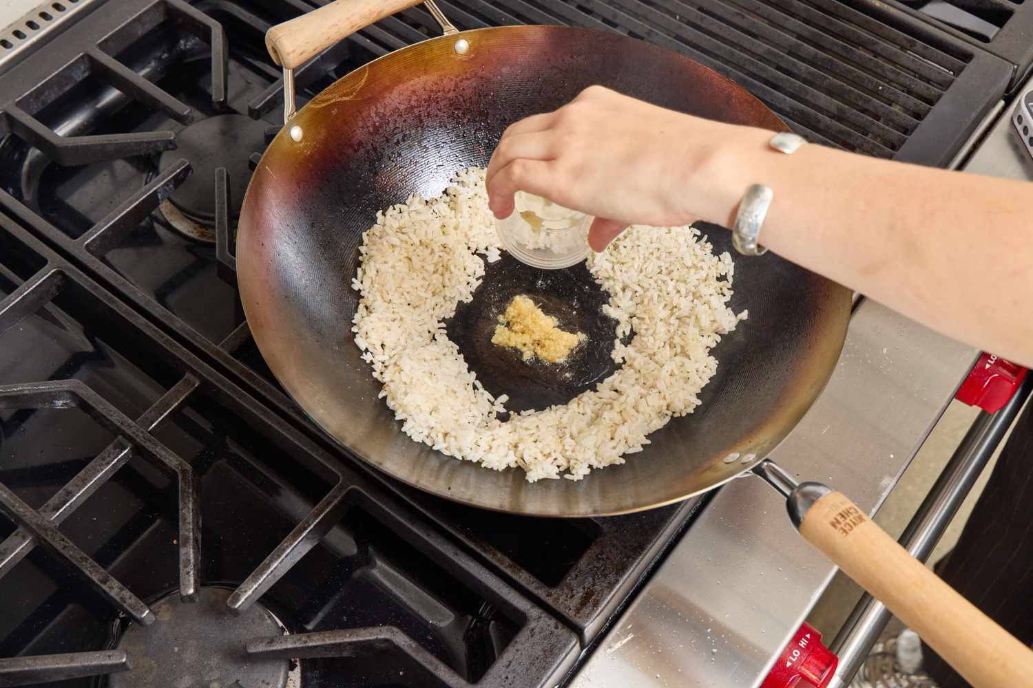 A person adds garlic to fried rice in the Joyce Chen Carbon Steel Wok