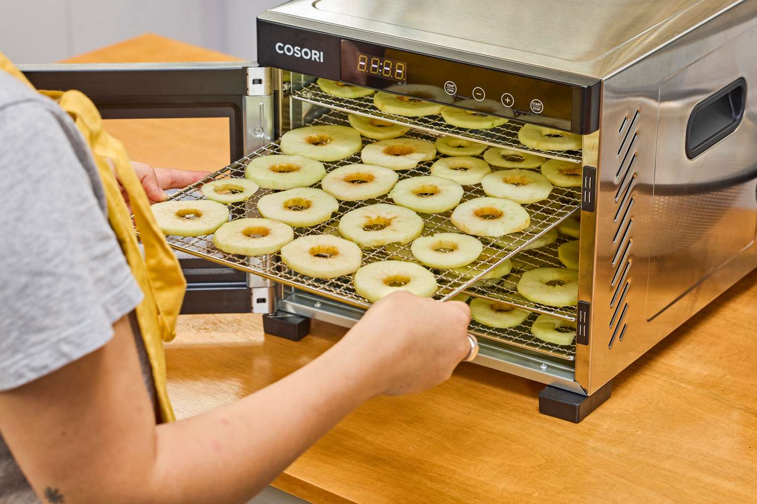 A person placing a food tray in COSORI Food Dehydrator