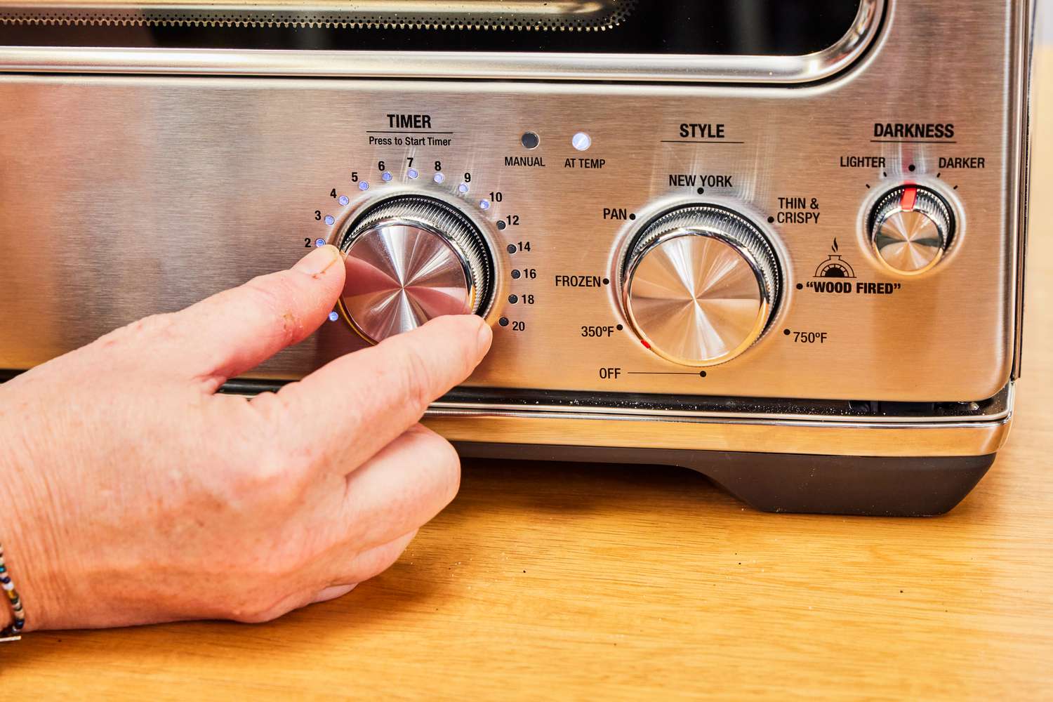 A person adjusts the temperature on the Breville Smart Oven Pizzaiolo Pizza Oven