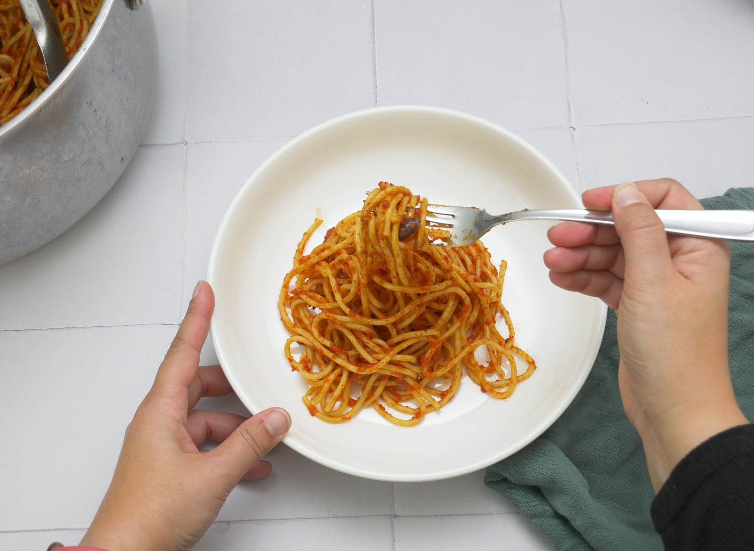 a person twirling sauced spaghetti from a pasta bowl