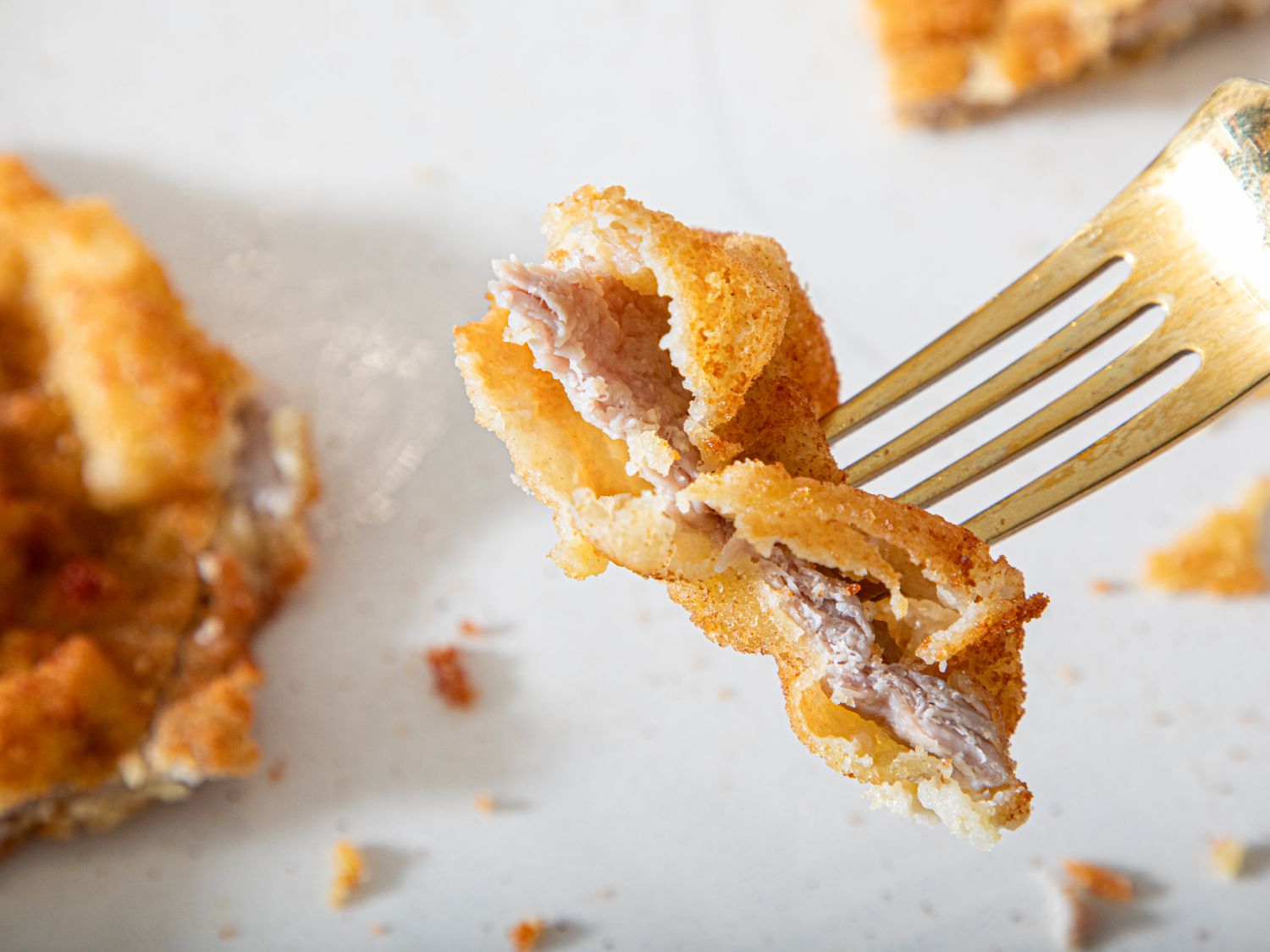 A fork holding a piece of fried food with meat inside close up view
