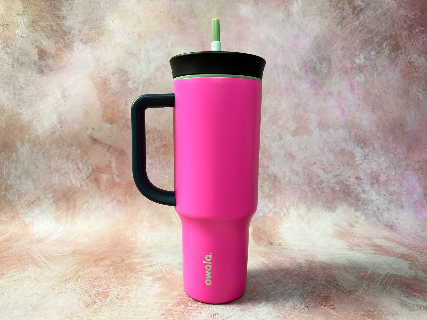 A pink Owala insulated tumbler on a pink surface.