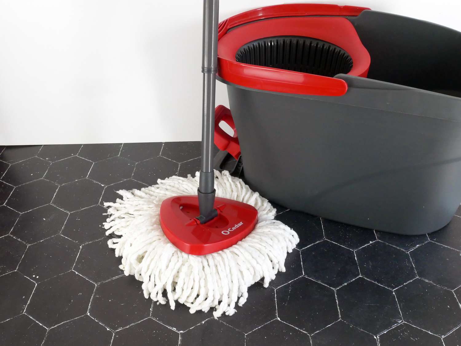 the o cedar mop with bucket behind it on a black tile surface