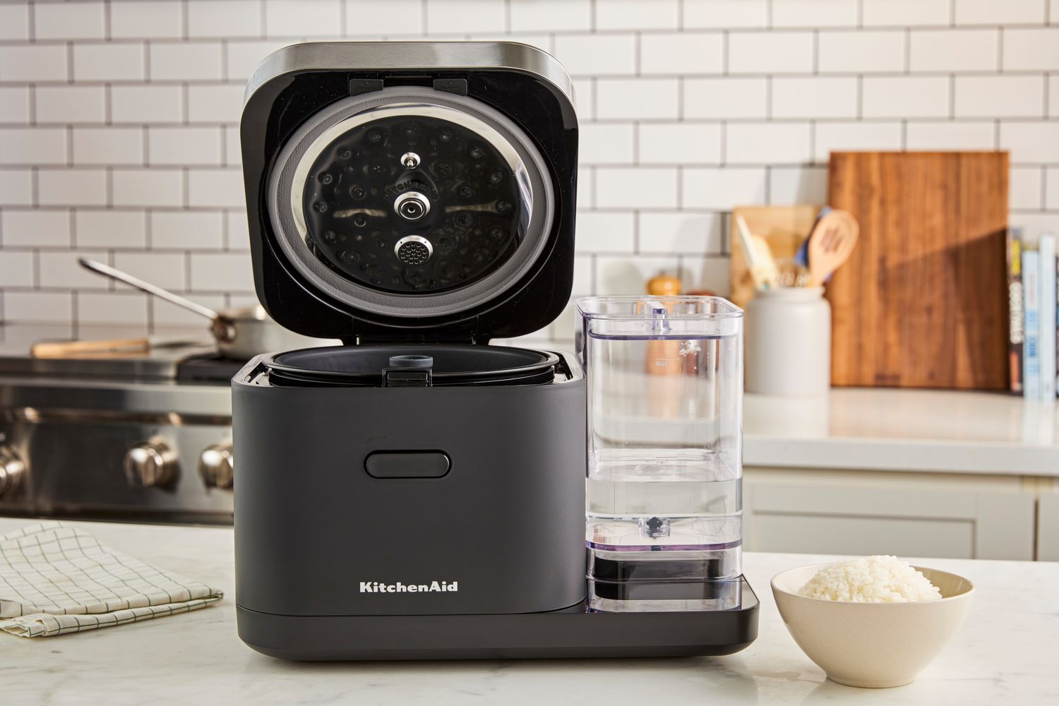 The KitchenAid rice cooker with its lid open on a kitchen countertop.