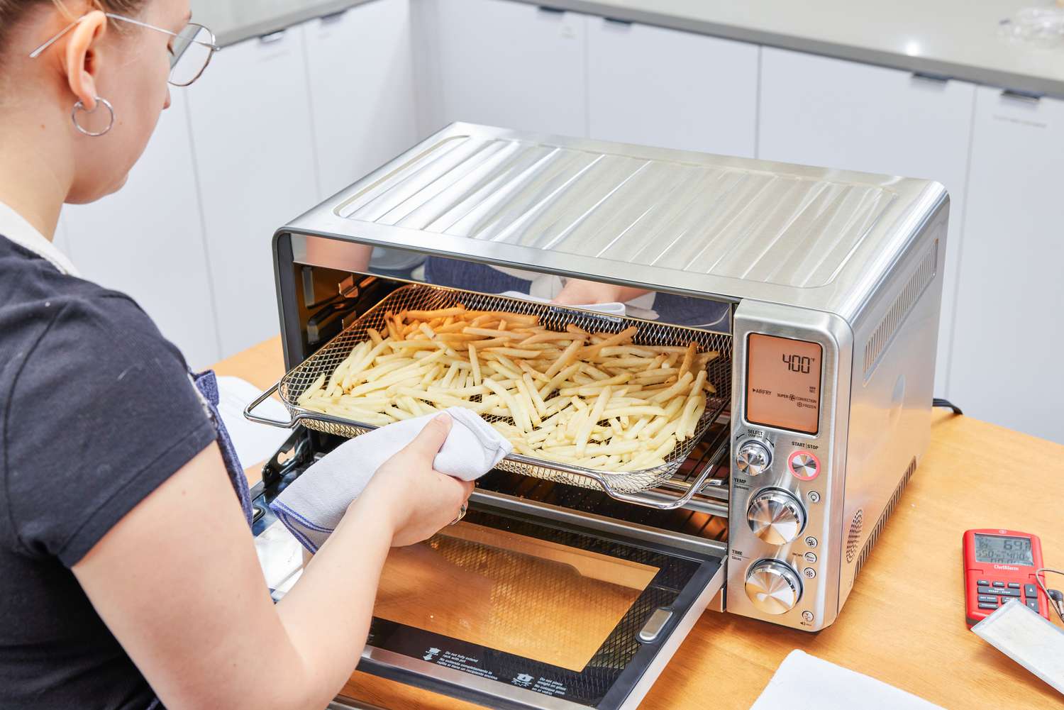 A person placing fries into the Breville the Smart Oven Air Fryer