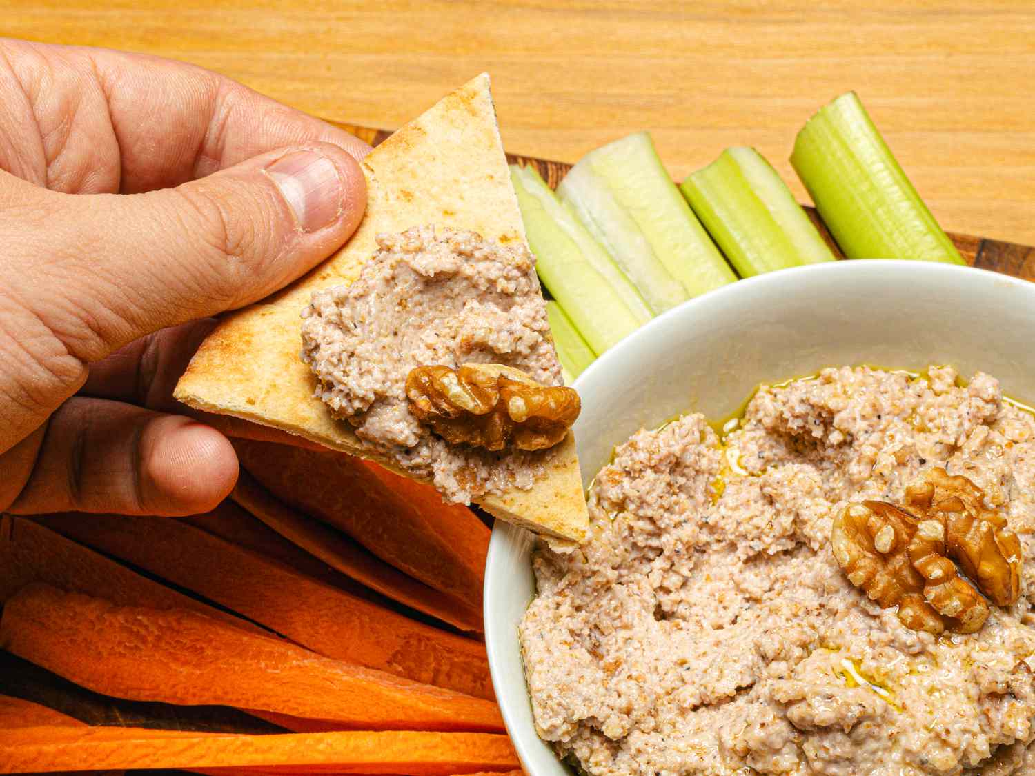 A bowl of walnut skordalia with pita carrot and celery sticks