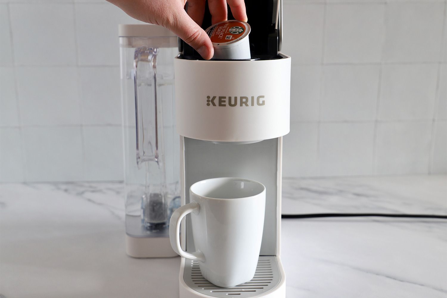 Person operating the Keurig K-Supreme Single Serve K-Cup Pod Coffee Maker