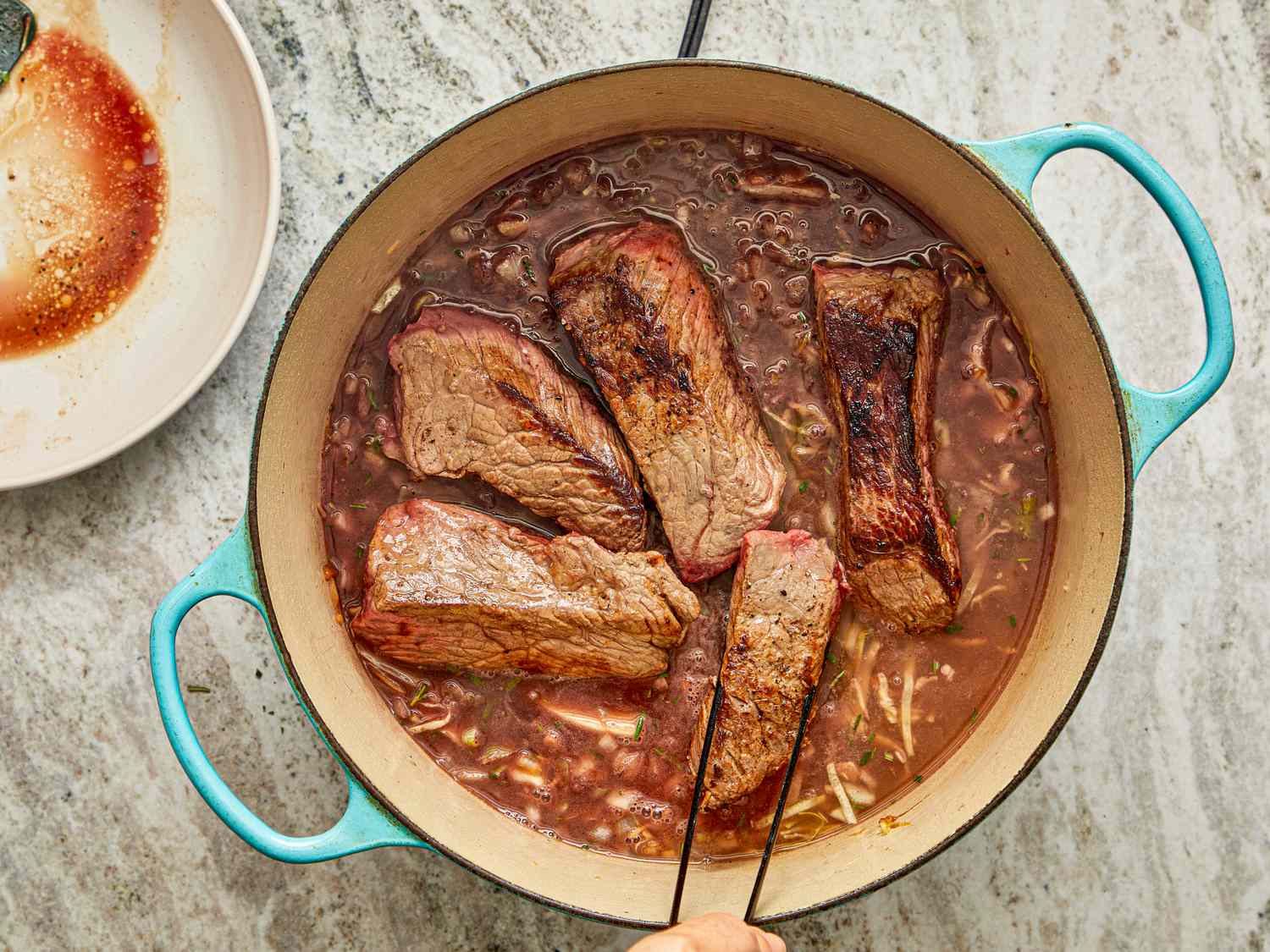 Cooking meat in a large pot with broth and seasonings