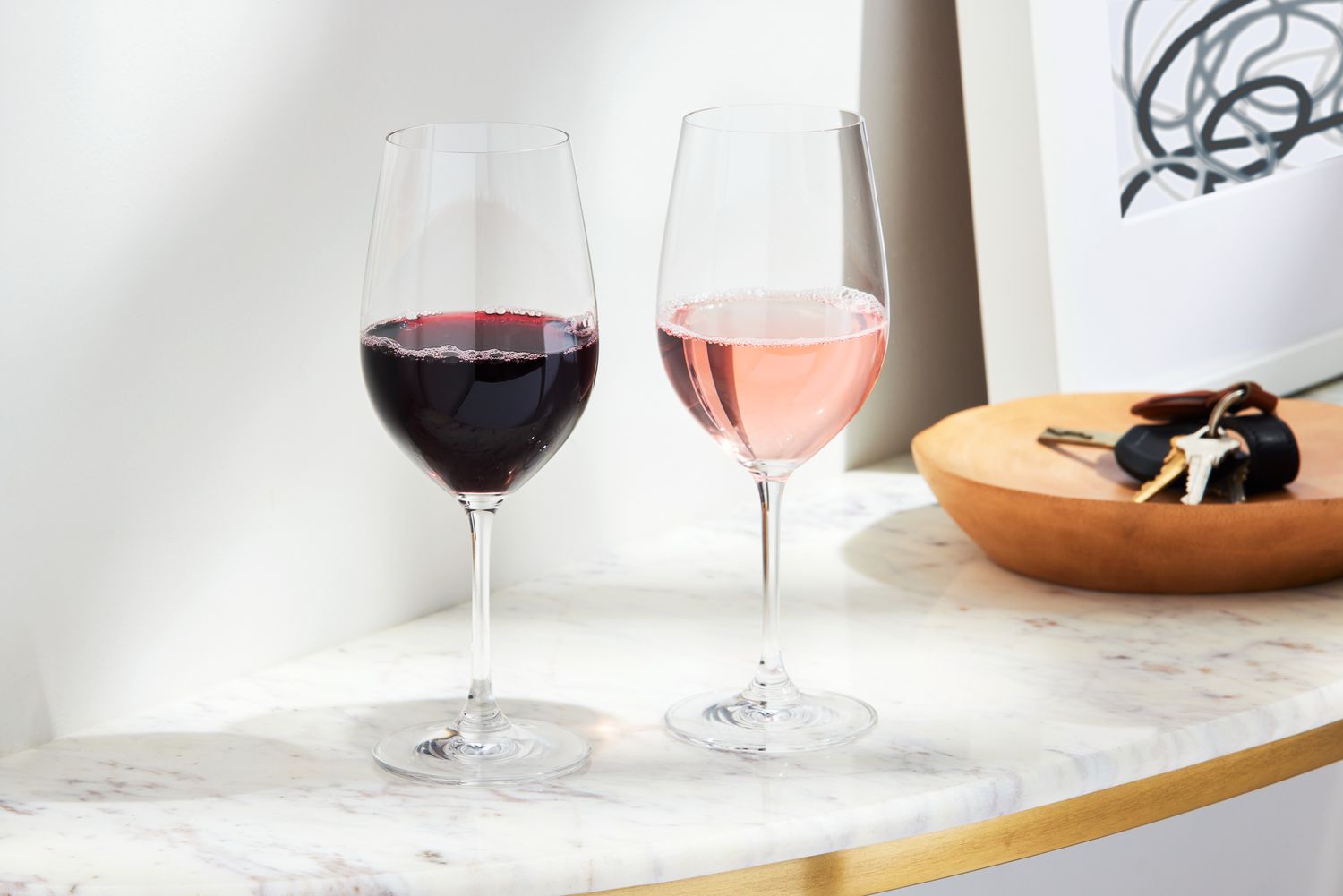Two Riedel VINUM Zinfandel/Riesling/Chianti Glasses on a marble table, one with red wine and one with rose