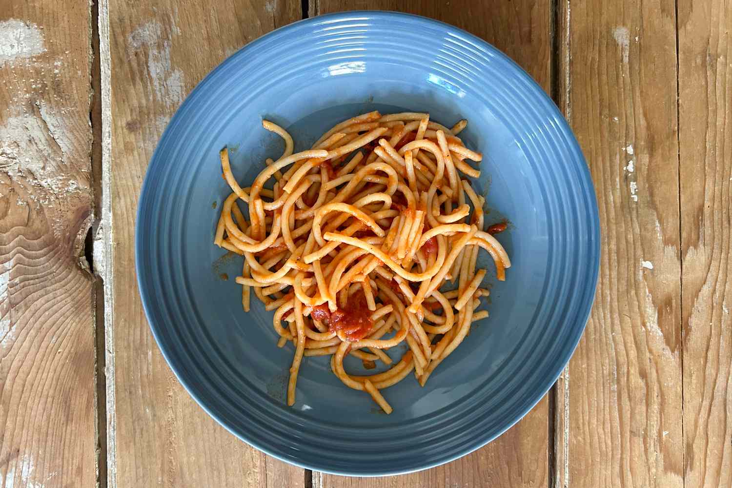 A blue glazed Le Creuset pasta bowl on a wooden table