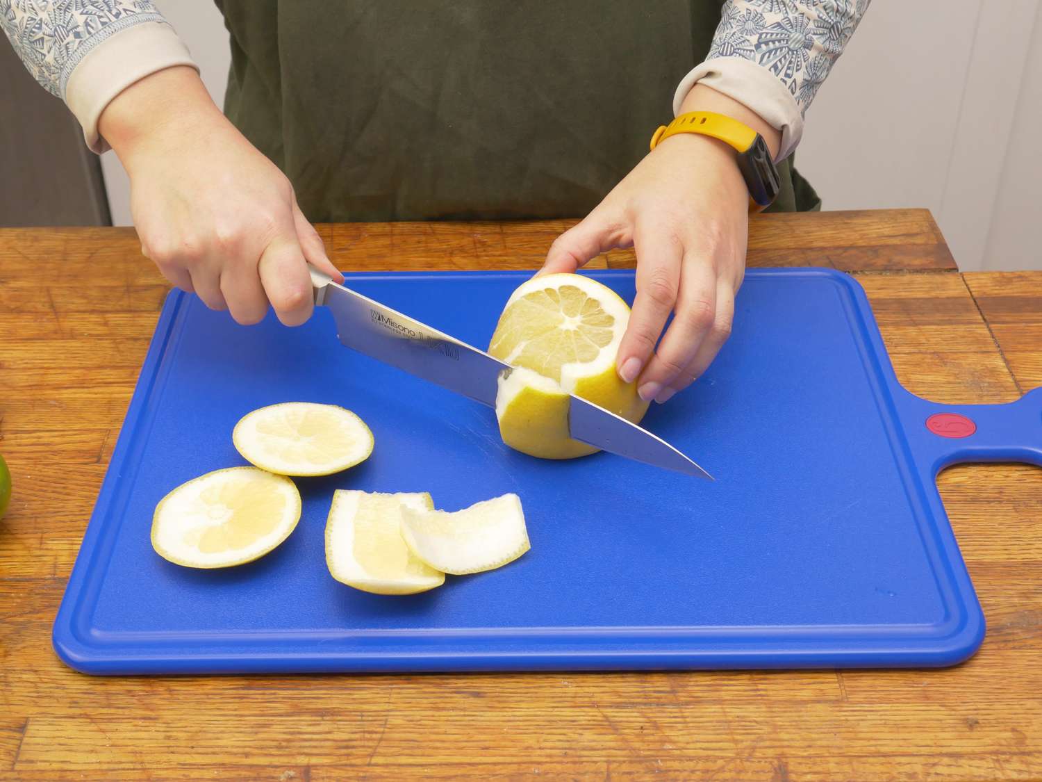 a person cutting the peel off a pomelo on the great jones board