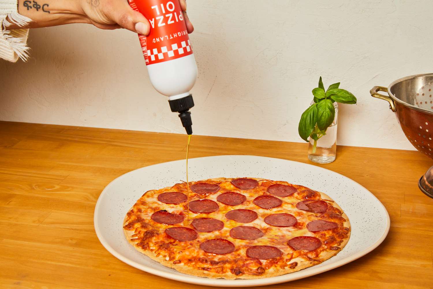 Brightland pizza oil being drizzled onto a whole pizza.